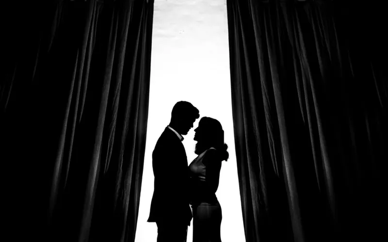 Couple silhouetted between dark curtains