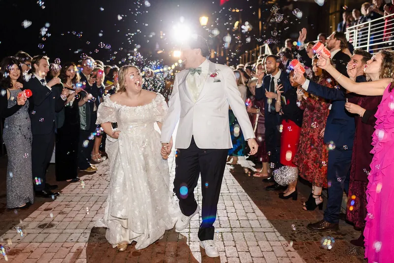 Newlyweds running through a bubble exit